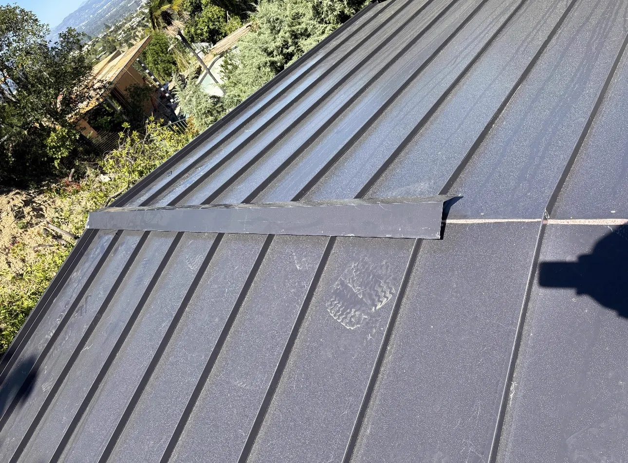 Close-up of a custom-bent transition flashing between two standing seam metal roof planes