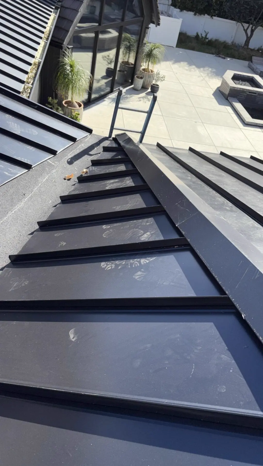 Standing seam metal roof hip and ridge detail with hand-bent black flashing over a peel-and-stick underlayment