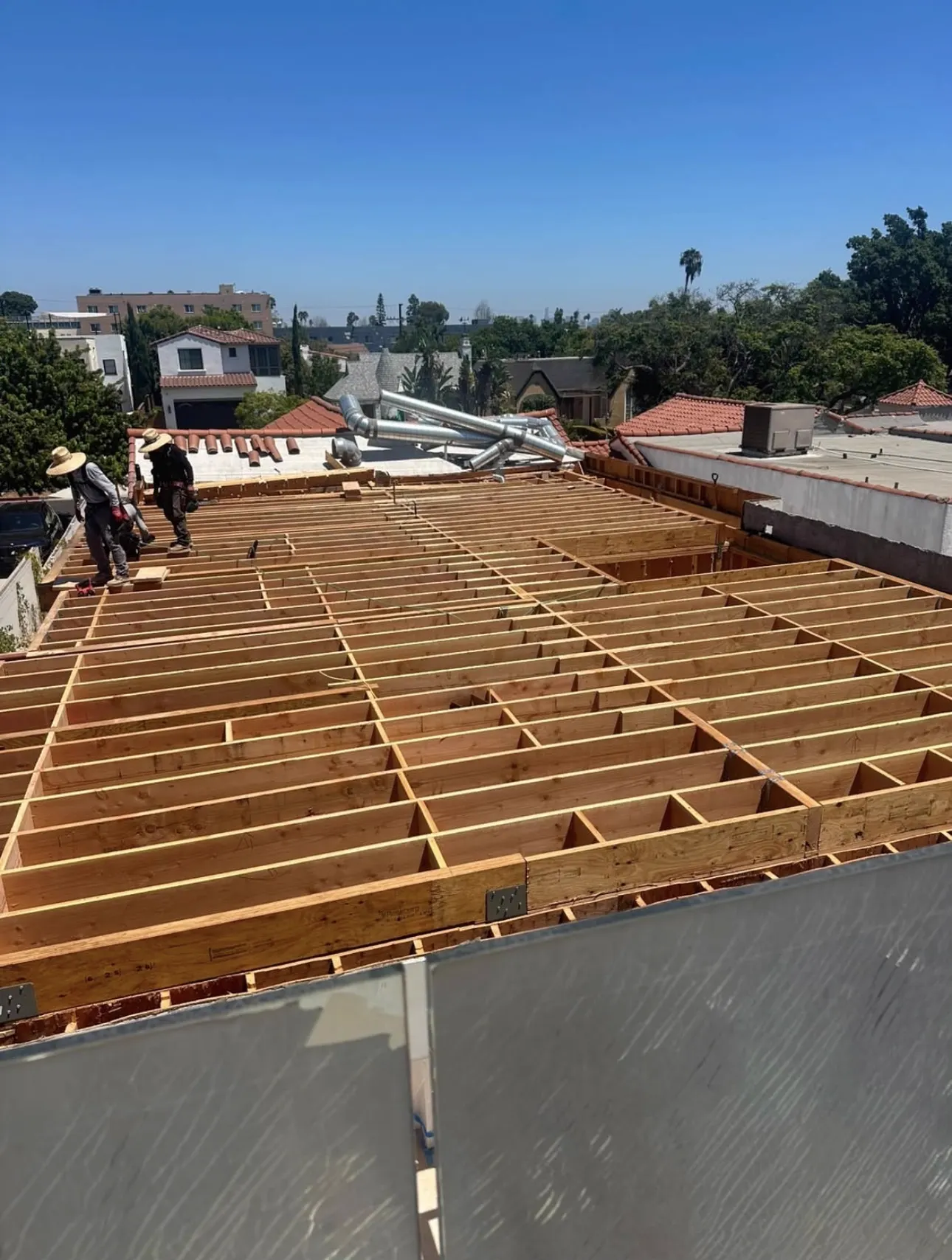 New wood roof framing and plywood decking prepared before a metal roof installation