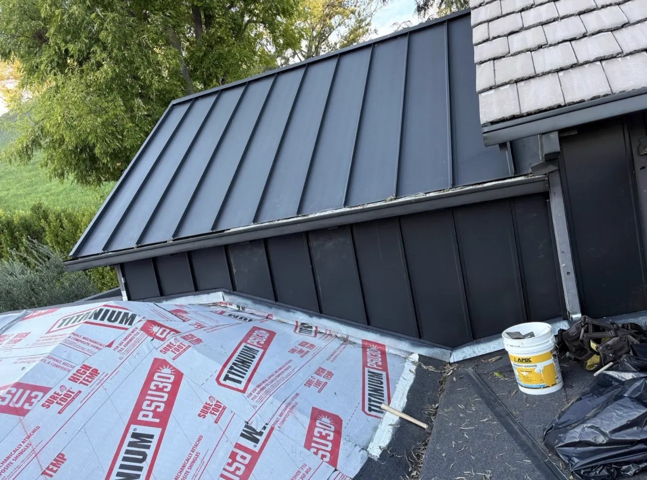 Standing seam metal dormer roof next to a shake roof with self-adhered underlayment in progress