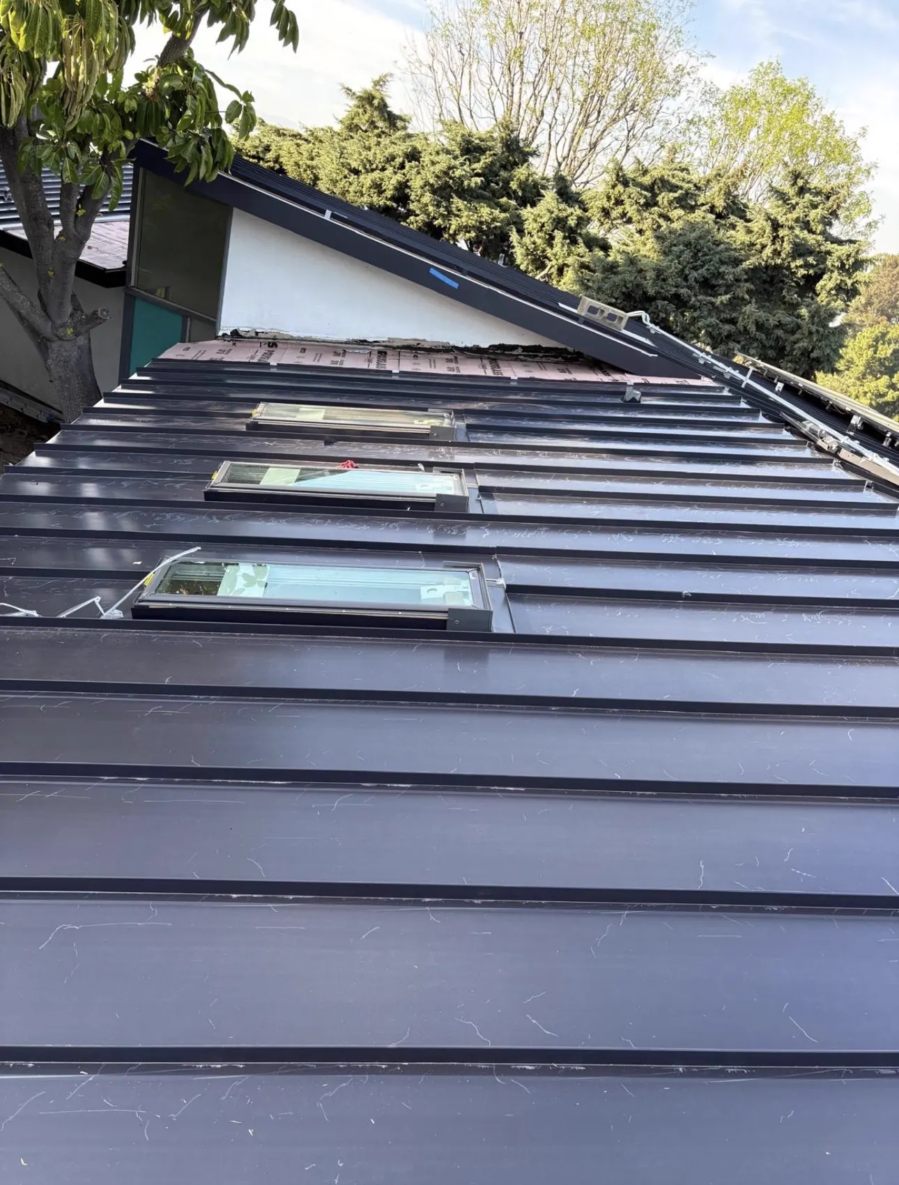 Three skylights framed into a standing seam metal roof slope during installation
