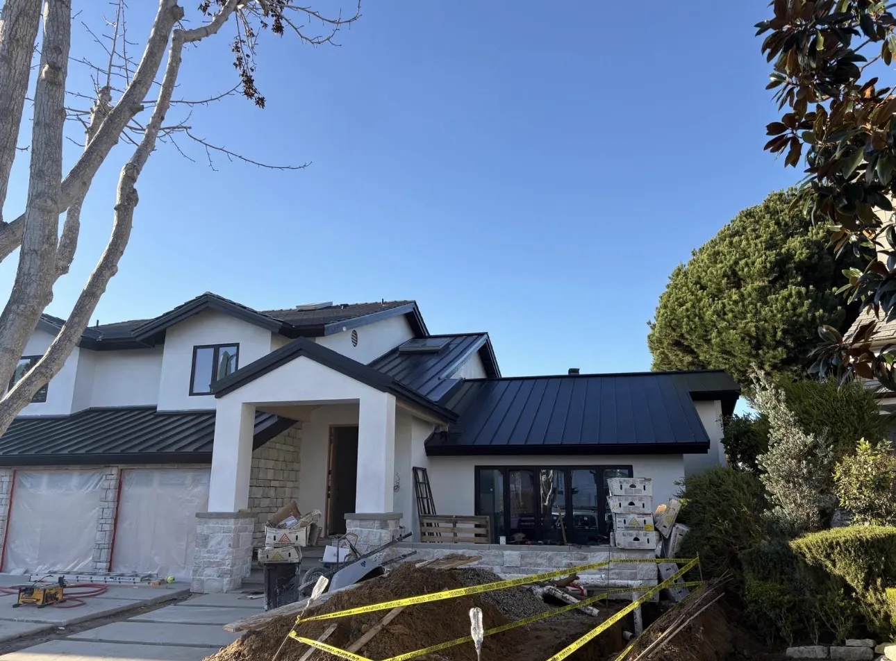 Completed matte black standing seam metal roof on a new two-story custom home with stucco and stone exterior